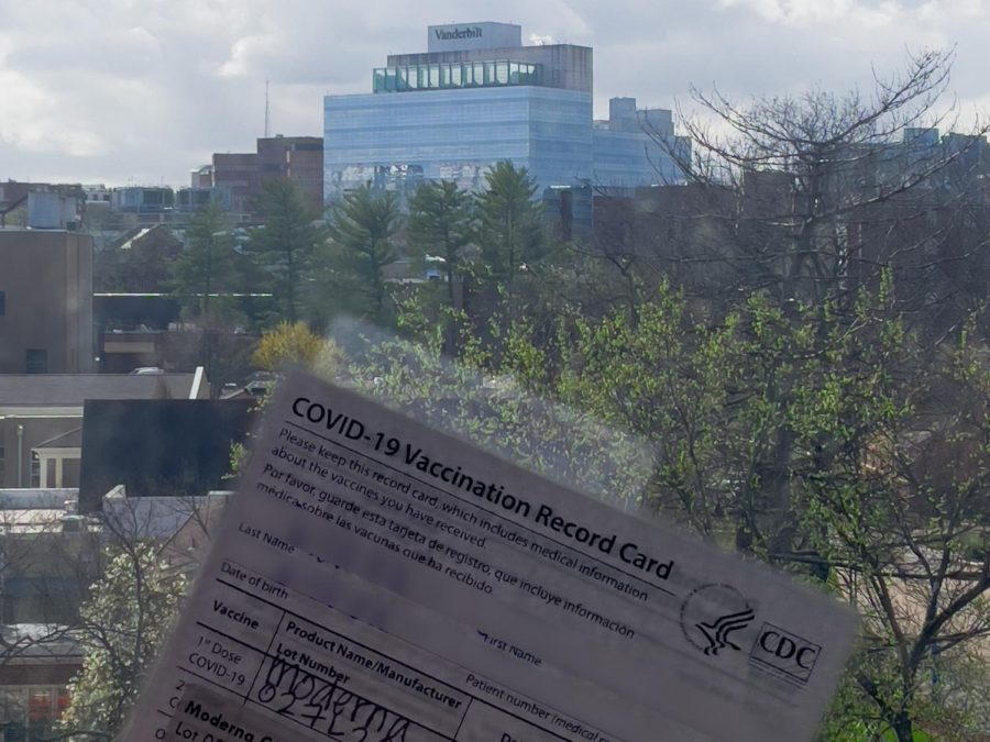 a covid-19 vaccine card is held against a window overlooking light hall