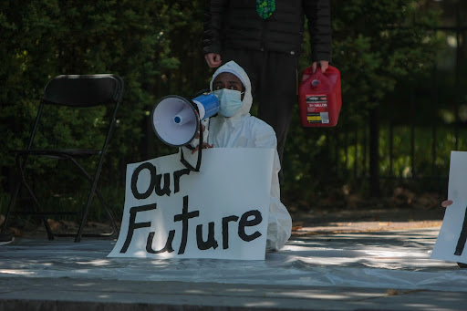 Ruth Aklilu at a Dores Divest protest, holding a handwritten sign that states “Our Future