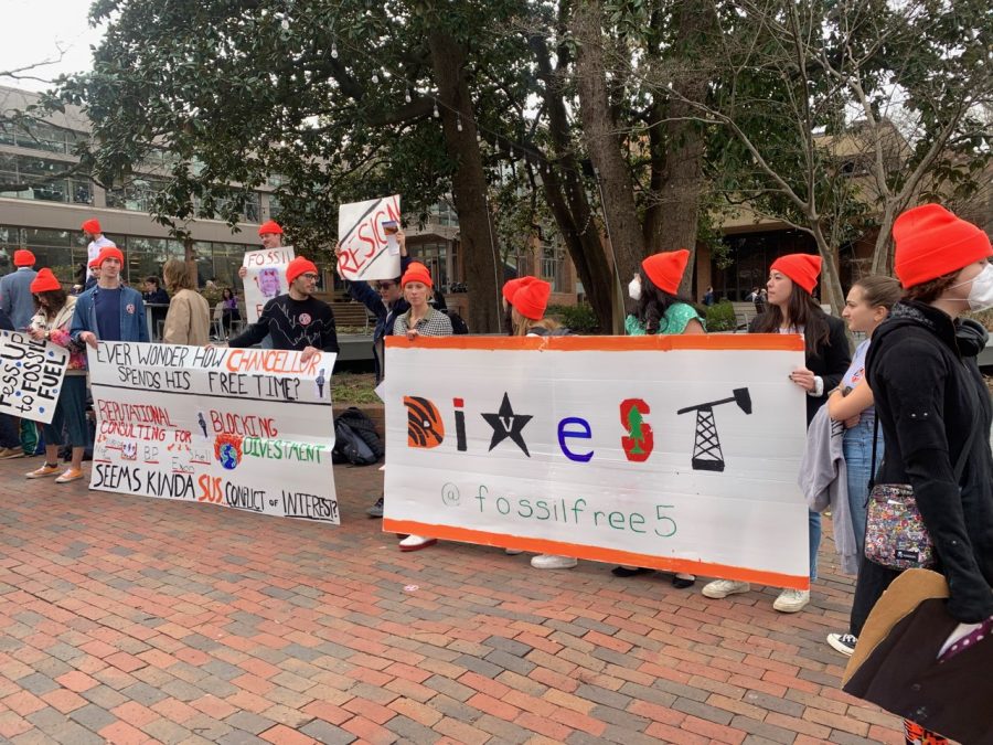 students wearing orange beanes holding signes to protest divestment