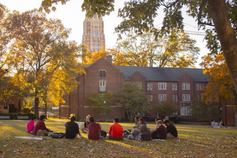 students sitting in a circle on alumni lawn n class with tolman hall in the background