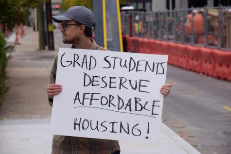 Graduate student protestor holding up a sign at the corner of 20th and Broadway, as photographed on Oct. 26, 2022.