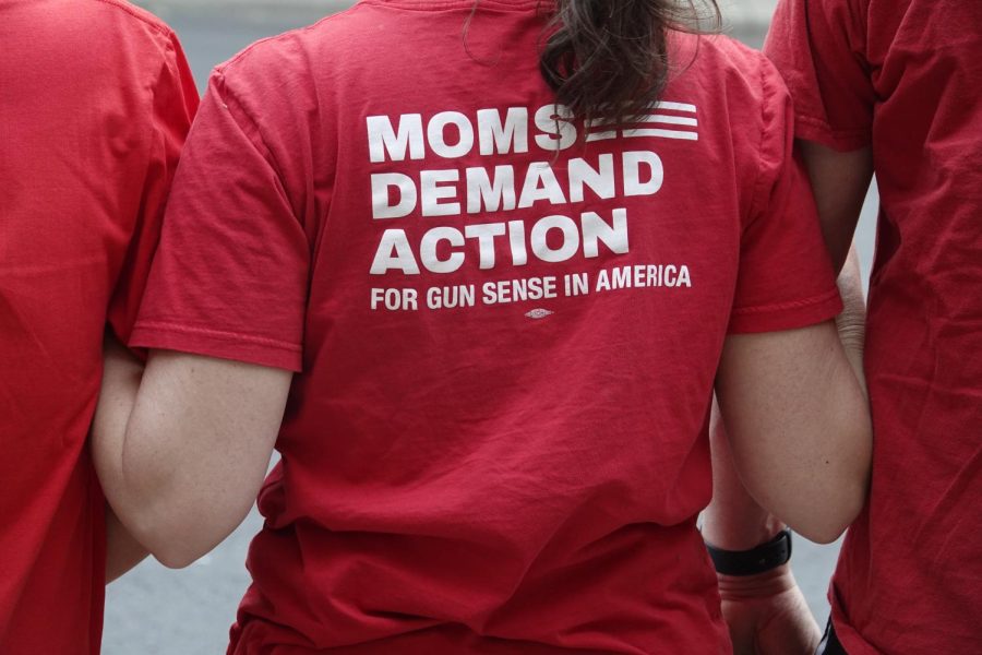 Woman wearing a “Moms Demand Action” shirt links arms with two others in support of common sense gun legislation, as photographed on April 18, 2023. (Hustler Staff/Duaa Faquih)