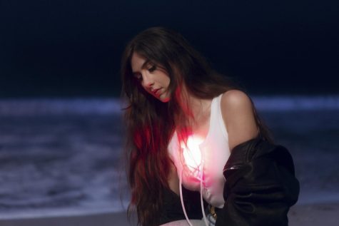 Portrait of Weyes Blood with a shining light on her white top. (Photo courtesy of Neil Krug)