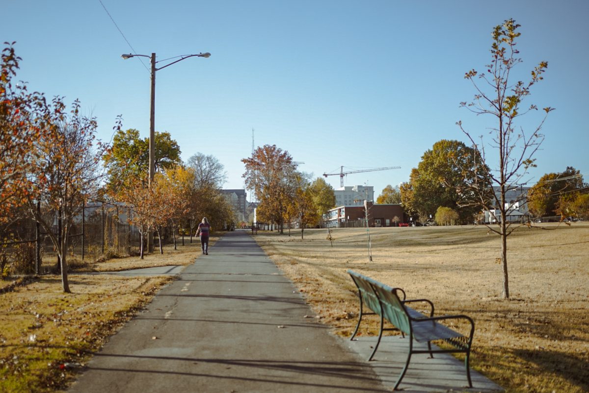 A person goes for a walk on the track next to Edgehill Community Memorial Garden and William Edmonton Homesite Park, with Belmont University in the distance, as photographed on Nov. 8, 2023. (Hustler Multimedia/Arianna Santiago)