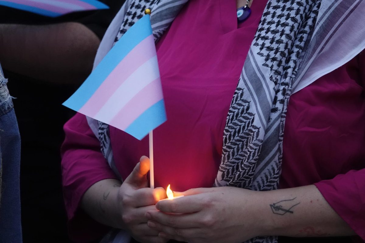 Vigil attendee holds candle and transgender pride flag, as photographed on Feb. 27, 2024. (Hustler Staff/Brina Ratangee)