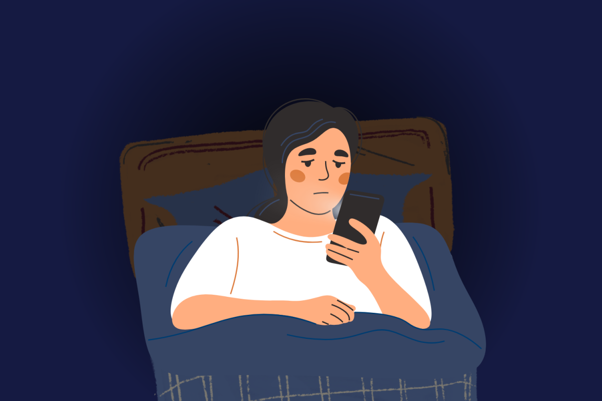 A student lies in bed looking at their phone (Hustler Multimedia/Lexie Perez).
