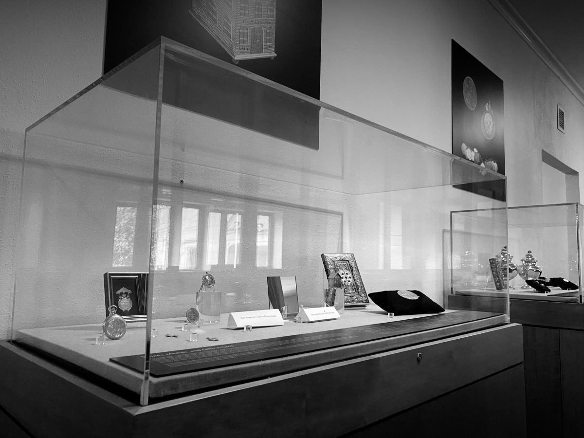 Black-and-white photograph of a display case full of artifacts in the “All That Glitters” exhibit, as photographed on March 8, 2024. (Hustler Multimedia/George Albu)