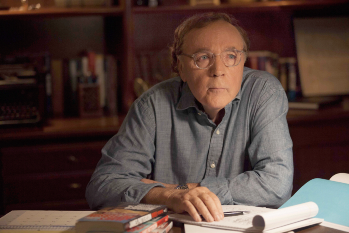 James Patterson (MA 70), author of over 260 New York Times bestselling books, photographed at his desk alongside some books he has written. (Photo courtesy of Vanderbilt University, photographed by Stephanie Diani)