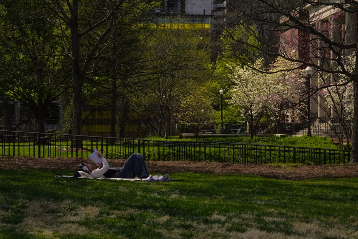 Student reads book on Wyatt Lawn by North House, as photographed on March 30, 2024. (Hustler Multimedia/Sofia Healy)