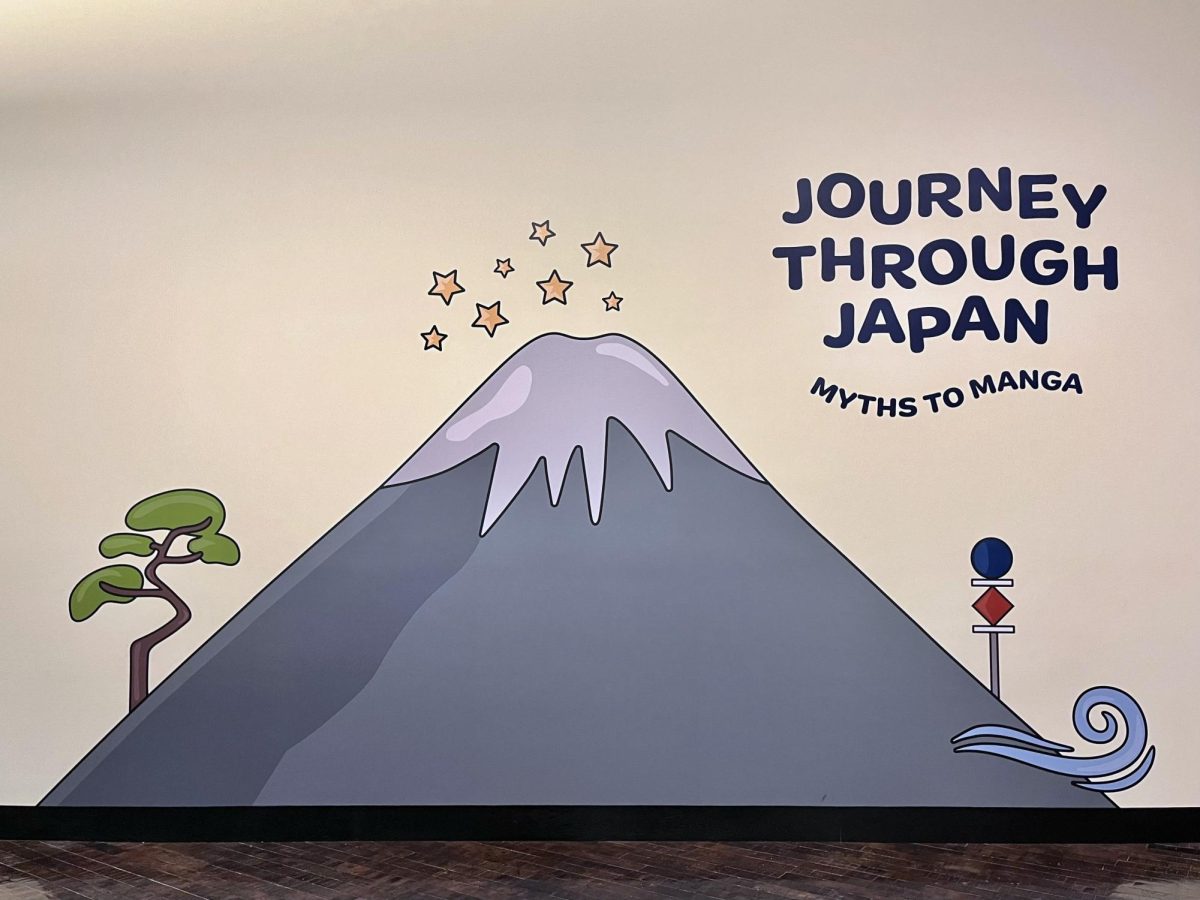 The entryway artwork for the “Journey through Japan: Myths to Manga” exhibition, displaying an illustrated mountain, tree, stars, road signs and a whirling breeze symbolizing the exhibit’s four thematic sections — the sky, sea, forest and city — as photographed on Dec. 22, 2024. (Hustler Multimedia/Jocelyn Ni)