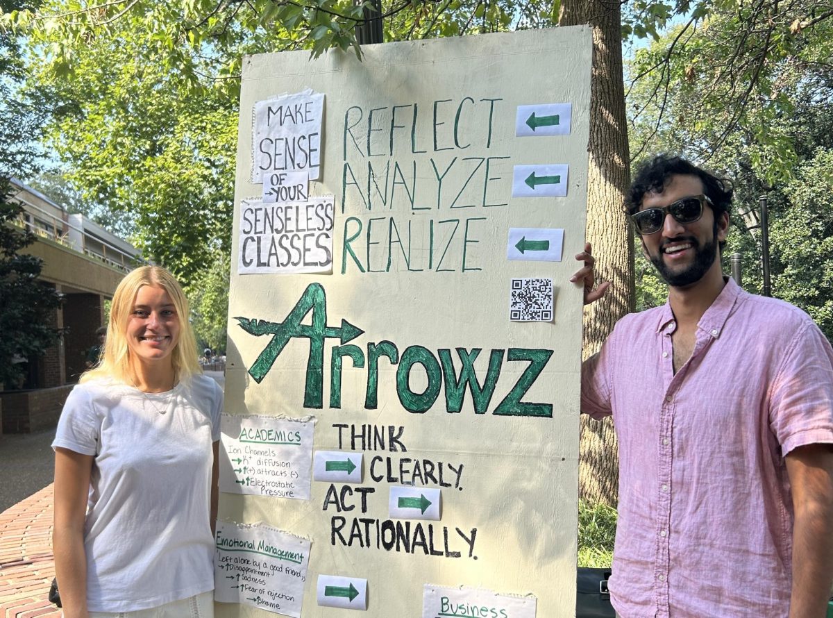 Two Arrowz team members stand by a poster display explaining their proposed app’s purpose outside of Rand, as photographed on Oct. 4, 2024. (Photo courtesy of Jamie Danis)