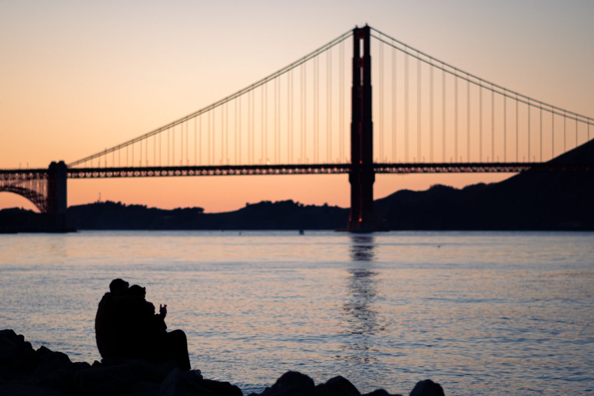 A couple sits on the rocks of the San Francisco harbor, as photographed Dec. 28, 2025. (Hustler Multimedia/Savannah Walske)