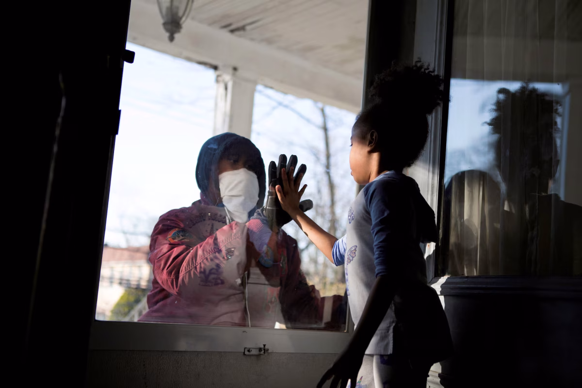 Hashim, an essential worker in the healthcare industry, greets his daughter through a closed door as he maintains social distance from his family while he works amid the coronavirus outbreak in New Rochelle, New York, April 11, 2020. (REUTERS/Joy Malone)